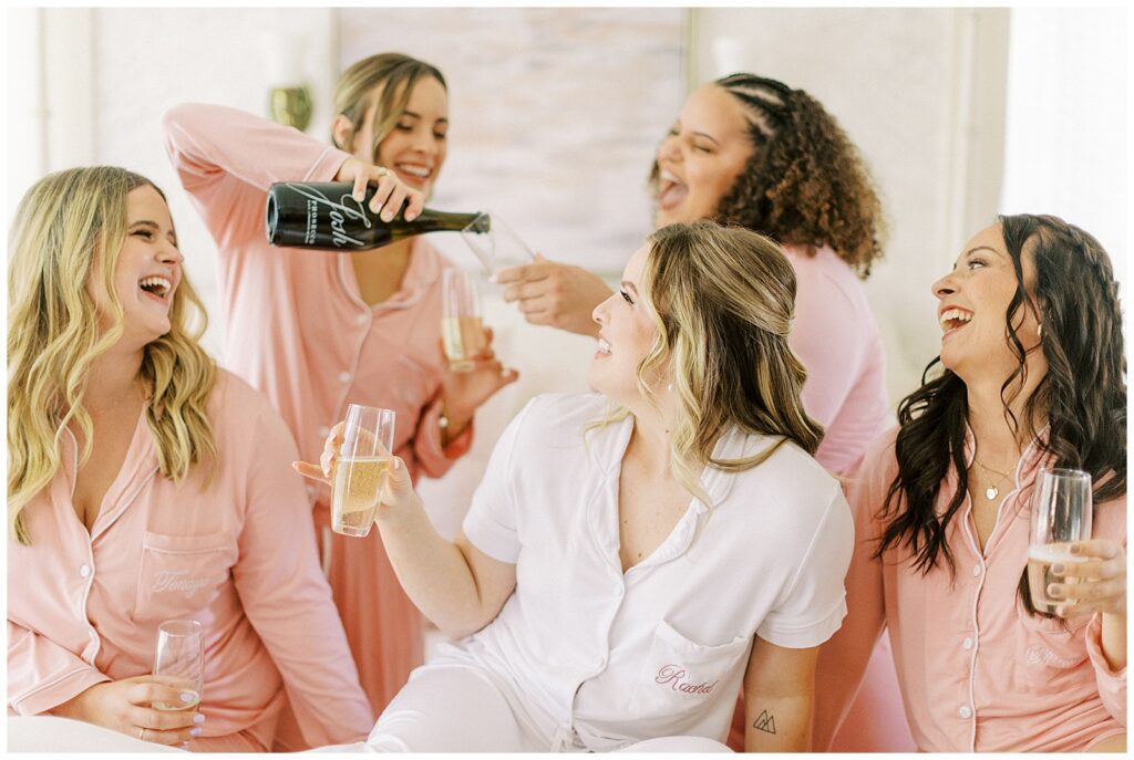 bride and bridesmaids pouring champagne and laughing at a lamoure vineyard wedding