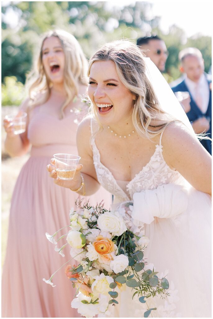 bride laughing and holding a cup of champagne at her lamoure vineyard wedding