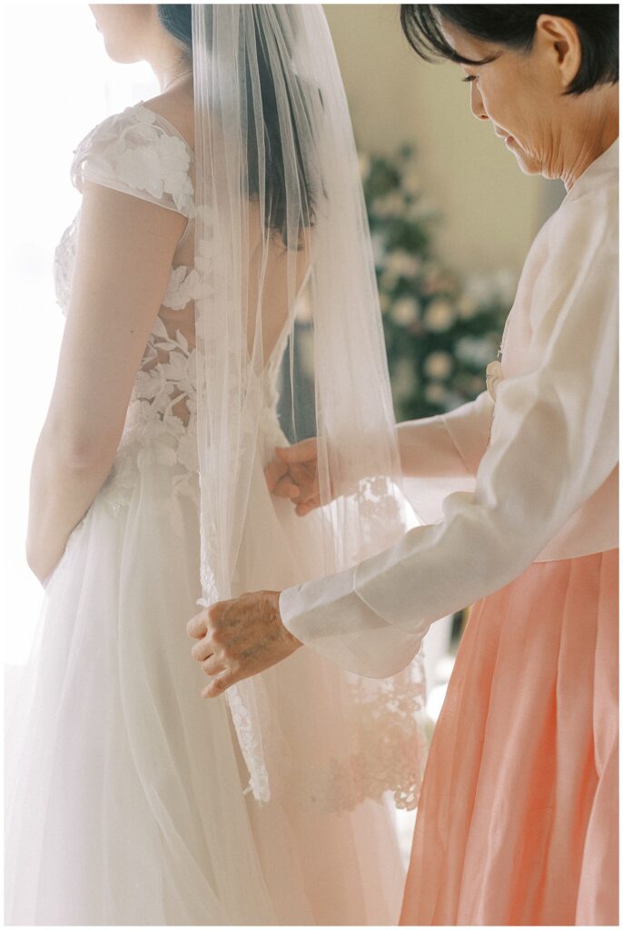 Mother of the bride hands adjusting the bride's veil.