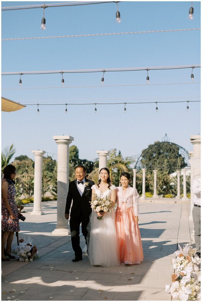 Bride walking down the aisle with her parents.