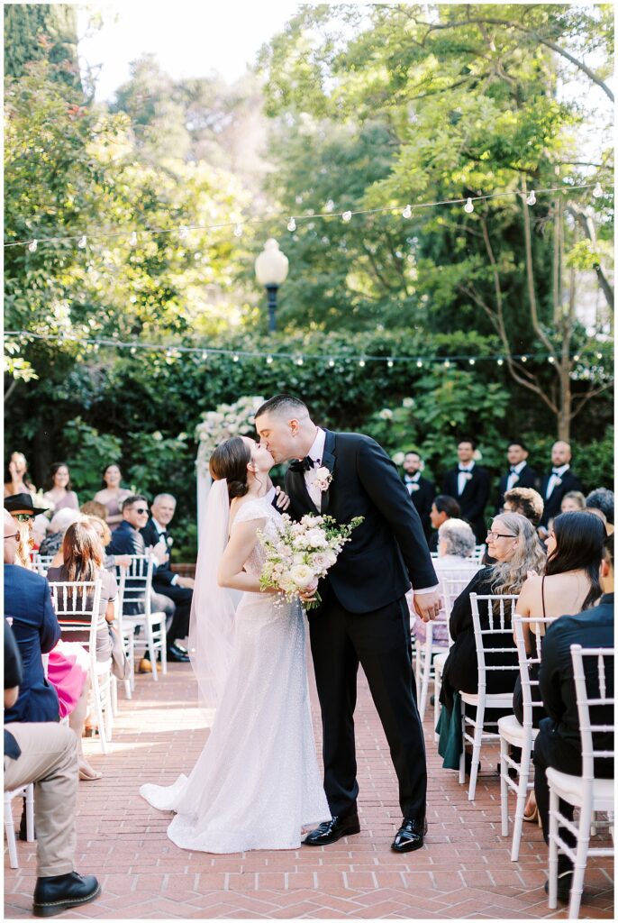 Bride and groom pause during their recessional to kiss their Vizcaya wedding.