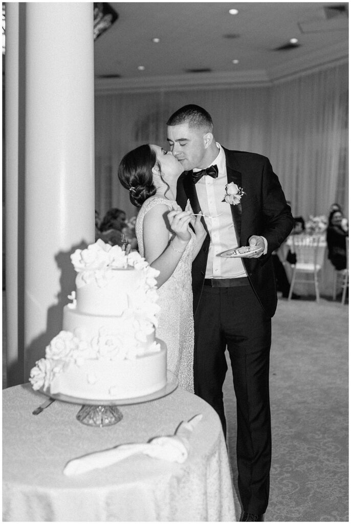 Black and white image of bride and groom kissing after they cut their wedding cake at their Vizcaya wedding.