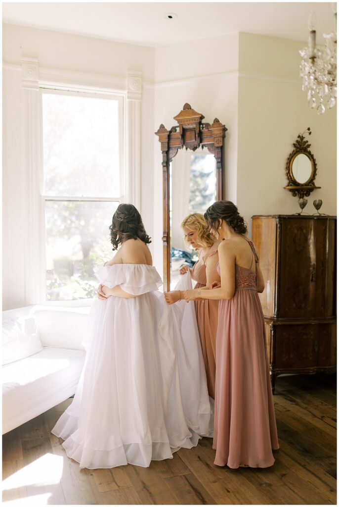 Bridesmaids help tie the bride's dress at Park Winters.