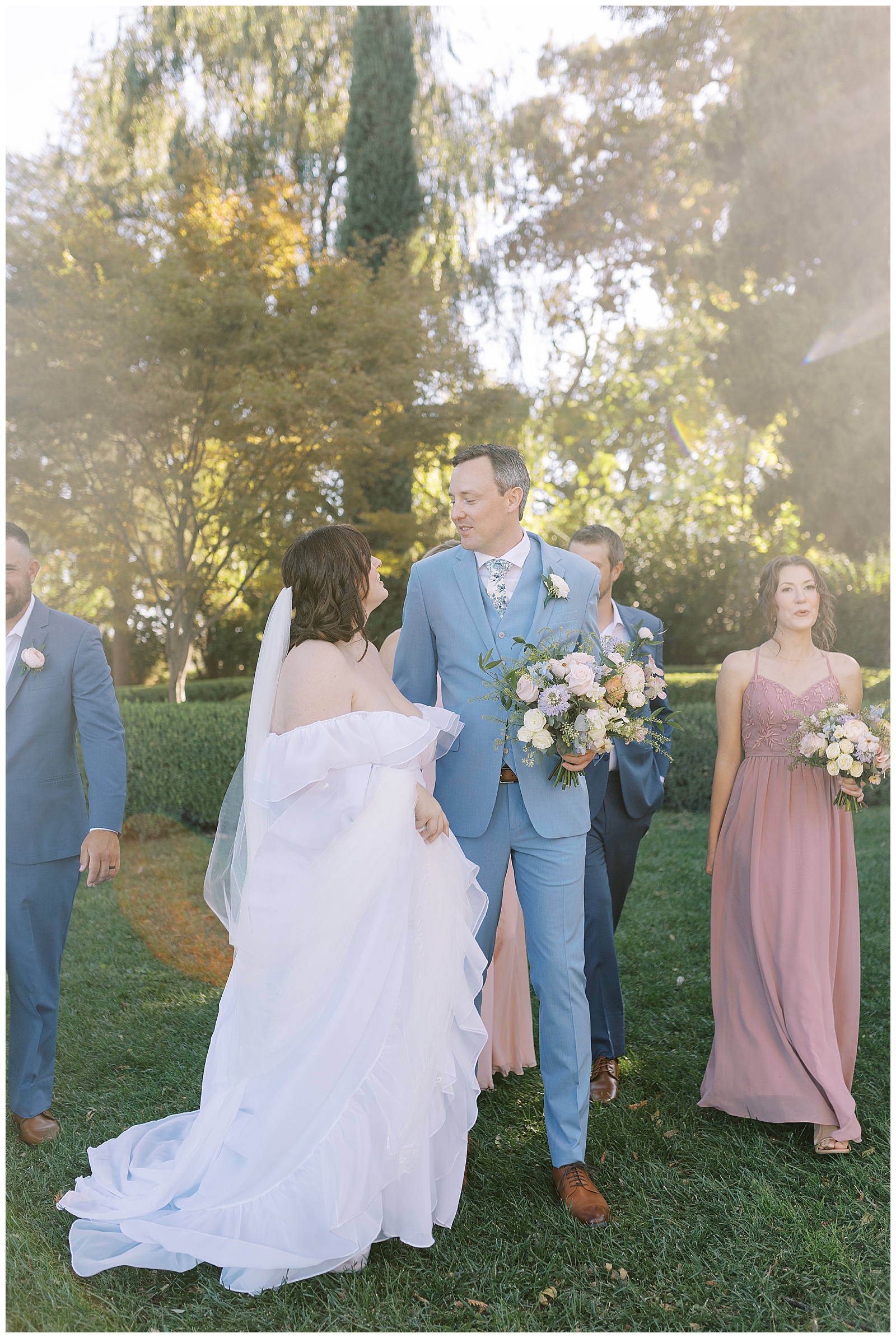 Bride and groom looking at each other while walking with their wedding party at Park Winters.