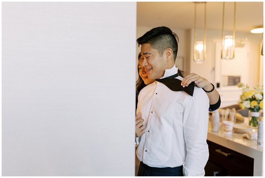 Groom's sister helps him adjust his bowtie.