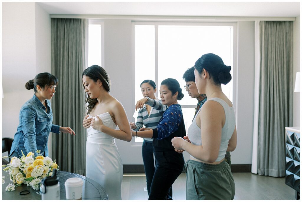 The bride and her sisters adjusting her wedding dress.