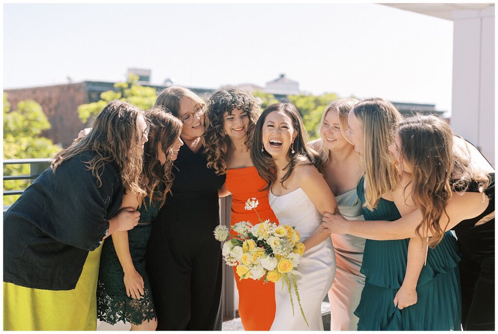 Bride laughing and surrounded by her friends.