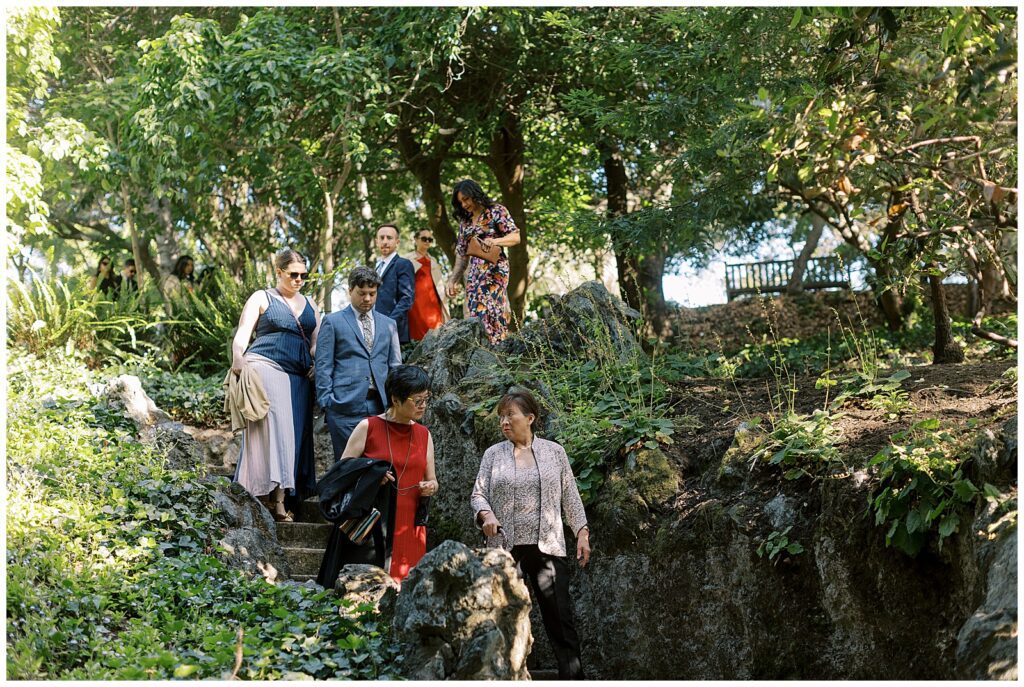 Guests walking down stairs towards the ceremony, surrounded by greenery.