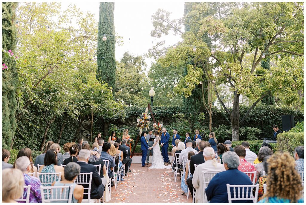 Guests seated and brides holding hands during their wedding ceremony.